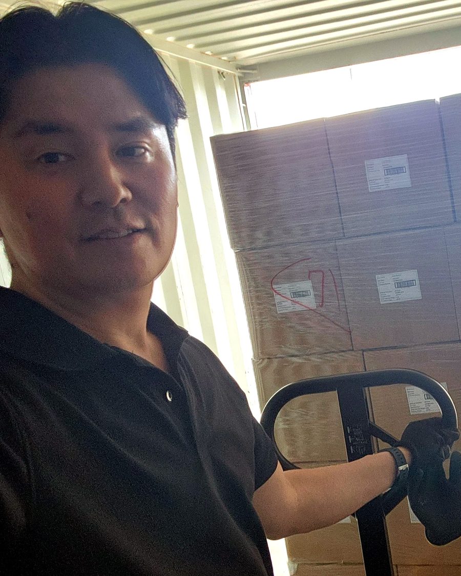 Hiroo Kato moving pallets in a shipping container with a pallet jack