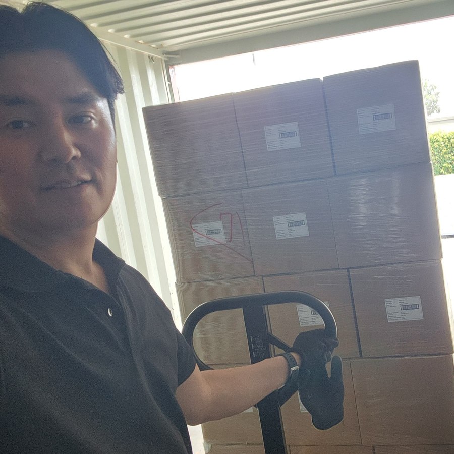 Hiroo Kato moving pallets in a shipping container with a pallet jack